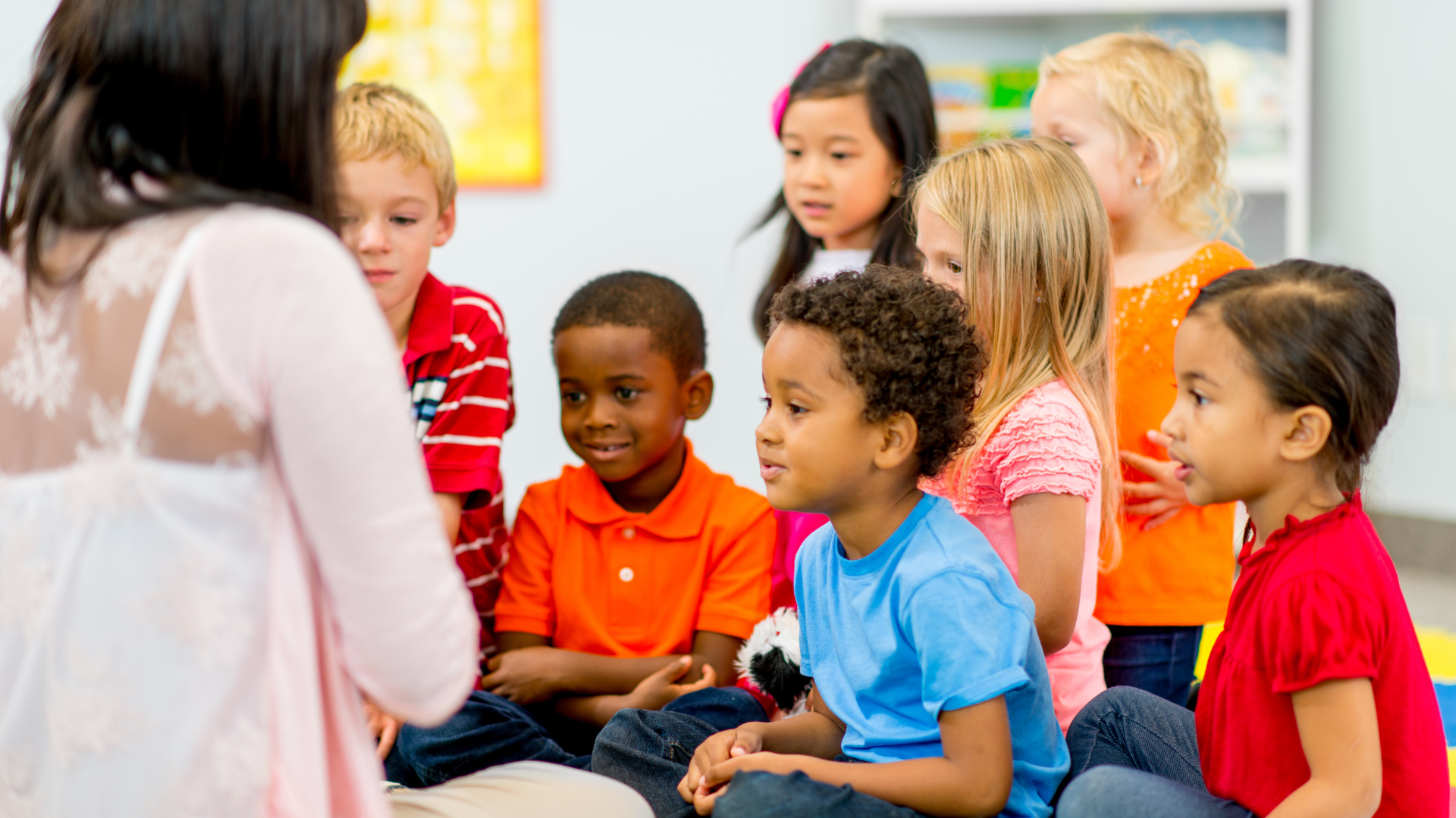 A group of children are sitting on the floor listening to a story.