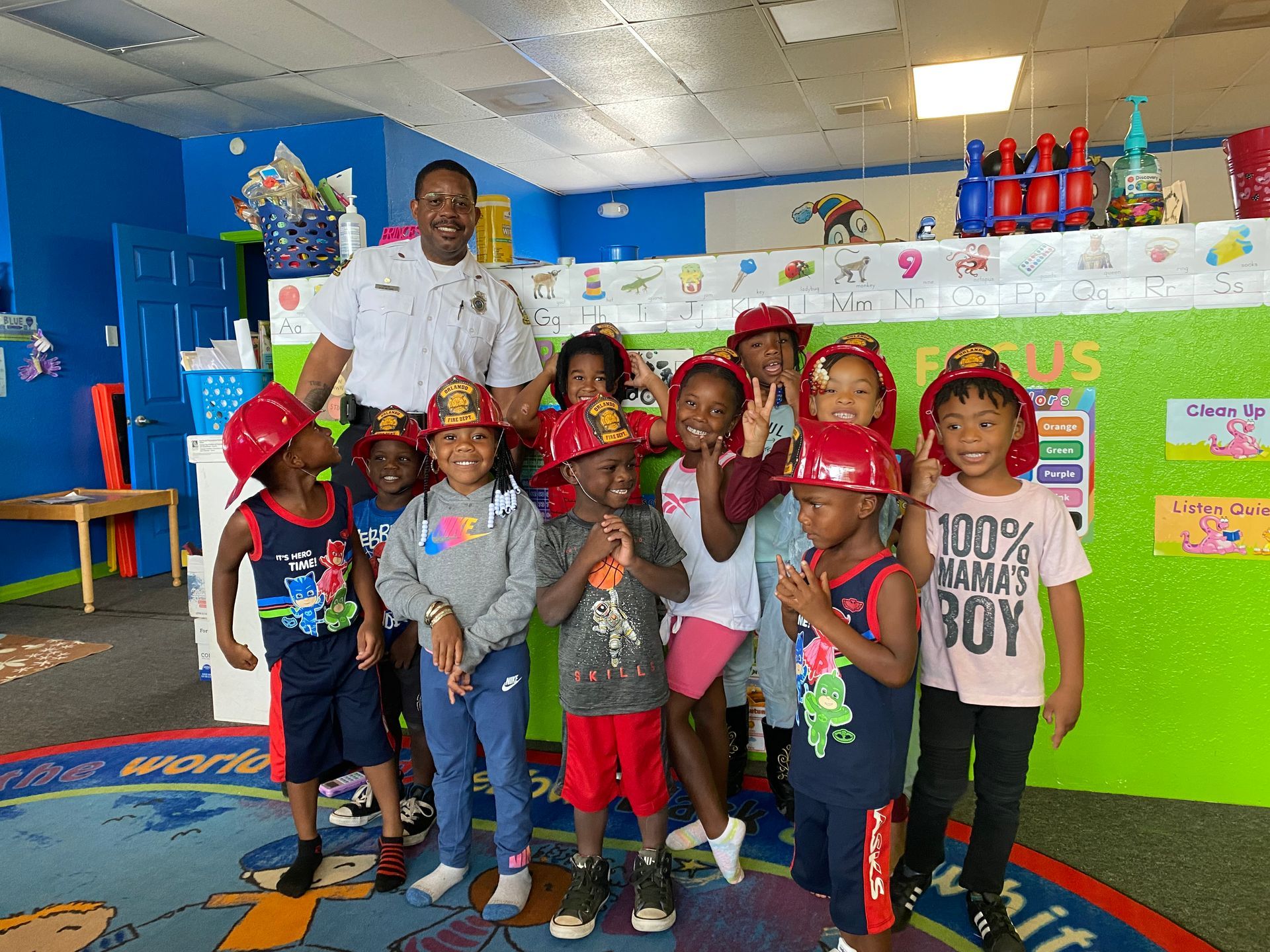 A group of children wearing fire helmets are posing for a picture with a police officer.
