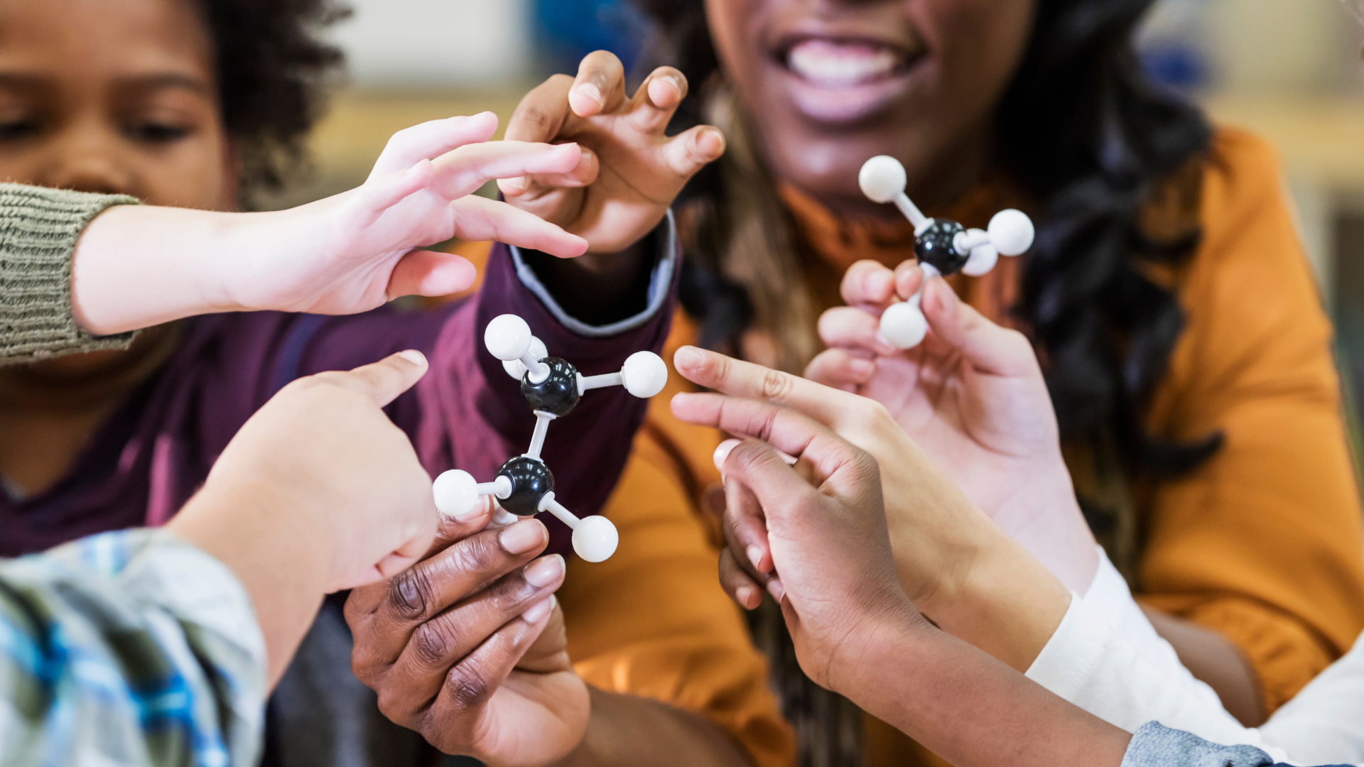 A group of children are holding a model of a molecule in their hands.