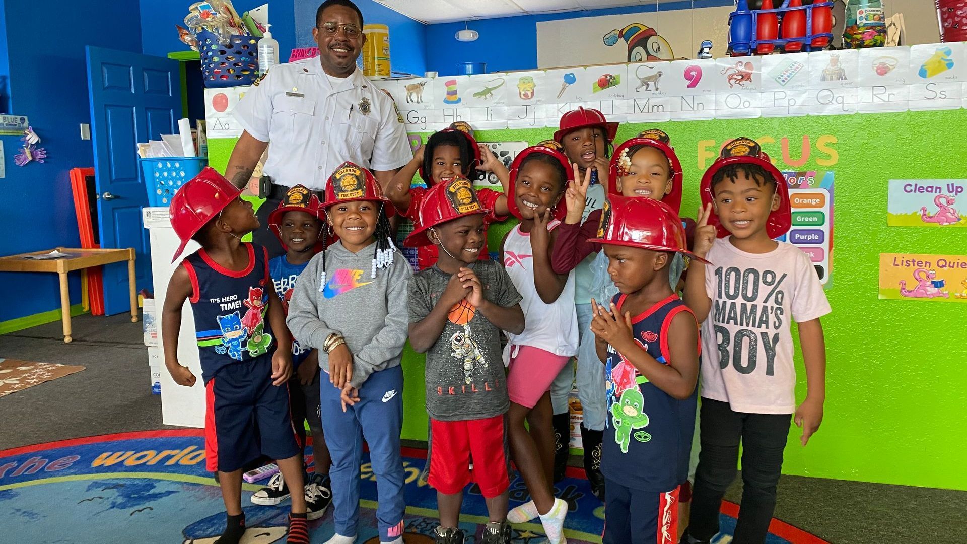 A group of children wearing fireman hats are posing for a picture.