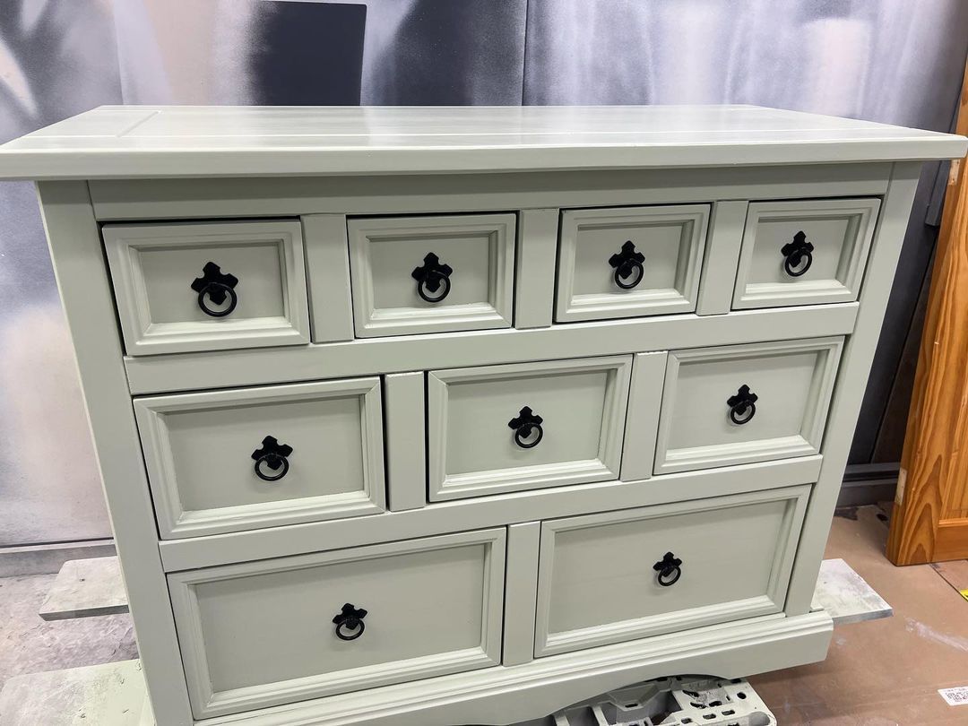 a white dresser with black handles is sitting on a table .