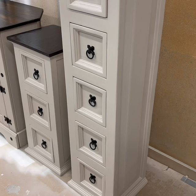 a white dresser with four drawers and black handles