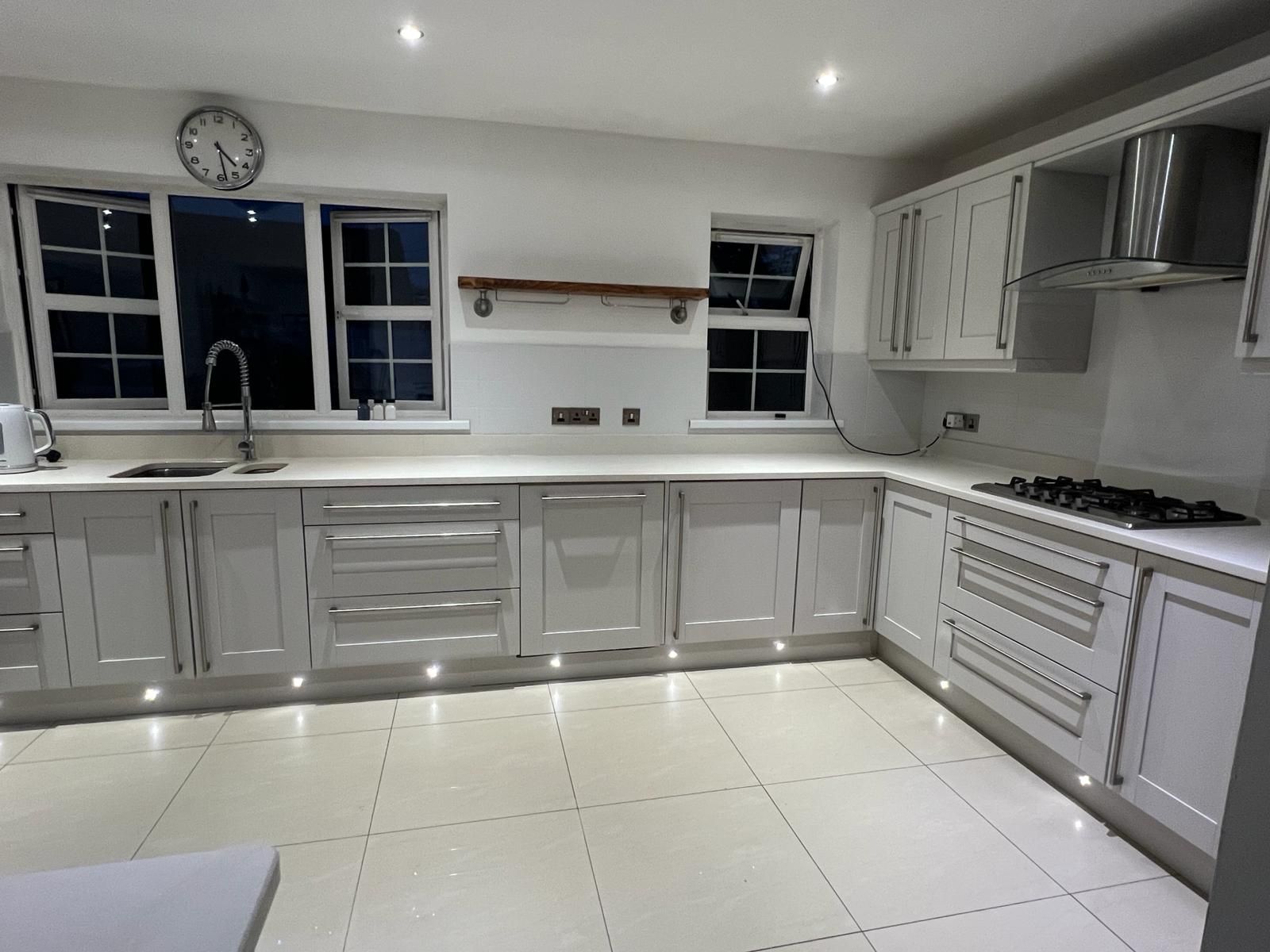 a kitchen with white cabinets and a clock on the wall