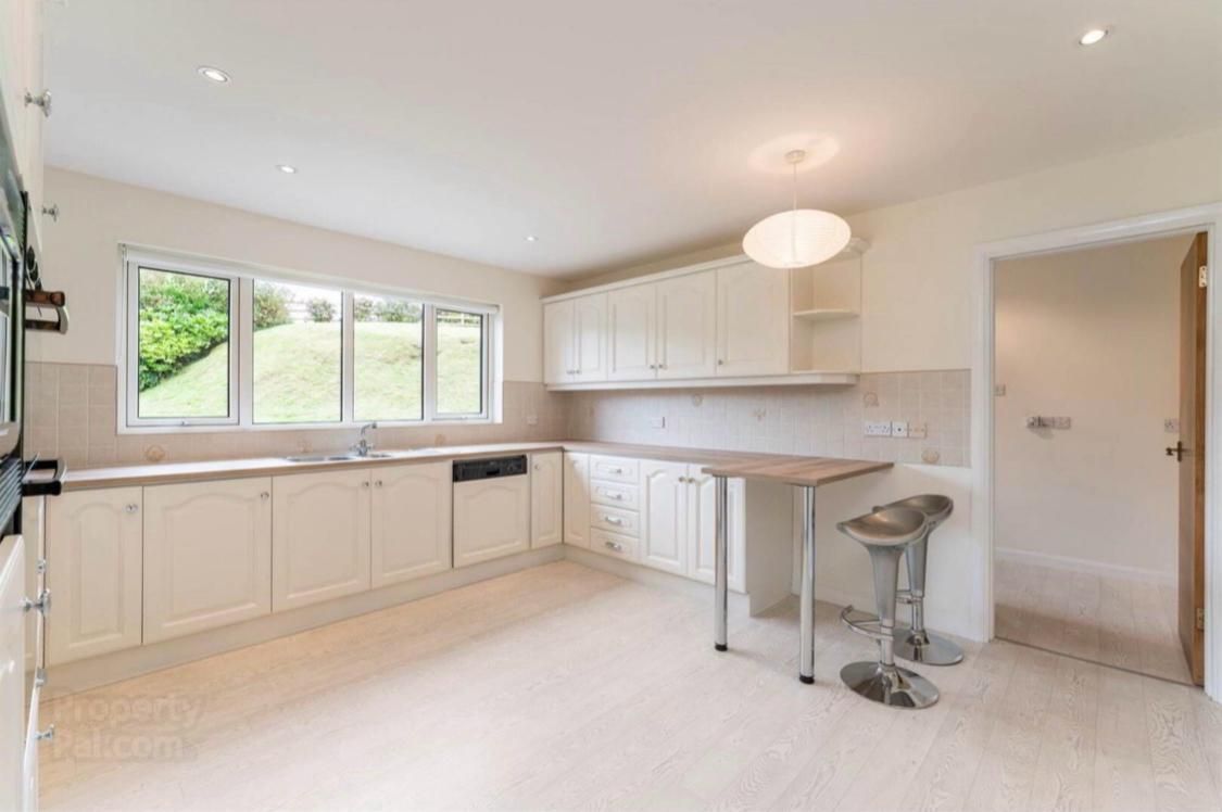 an empty kitchen with white cabinets , a table , and a window .