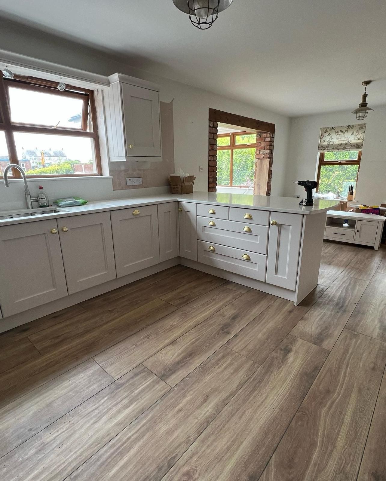 a kitchen with white cabinets and wooden floors and a sink .