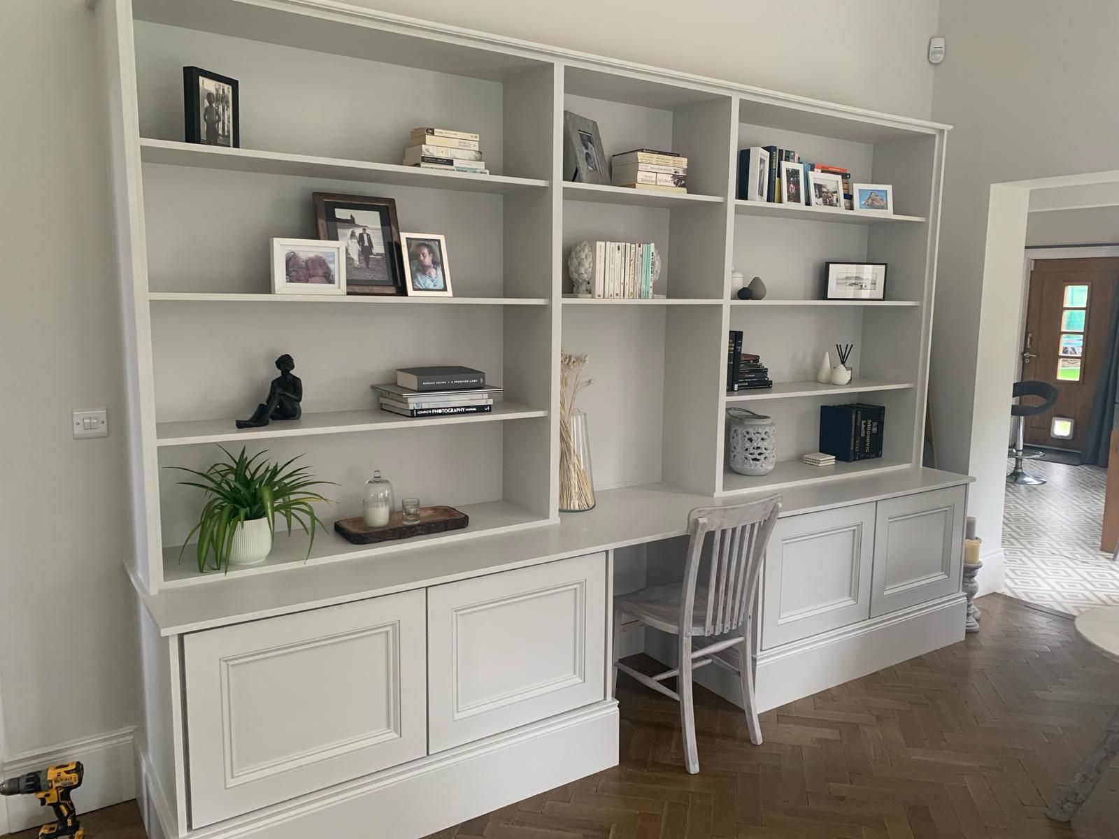 a large white bookshelf with a desk and chair in a living room .