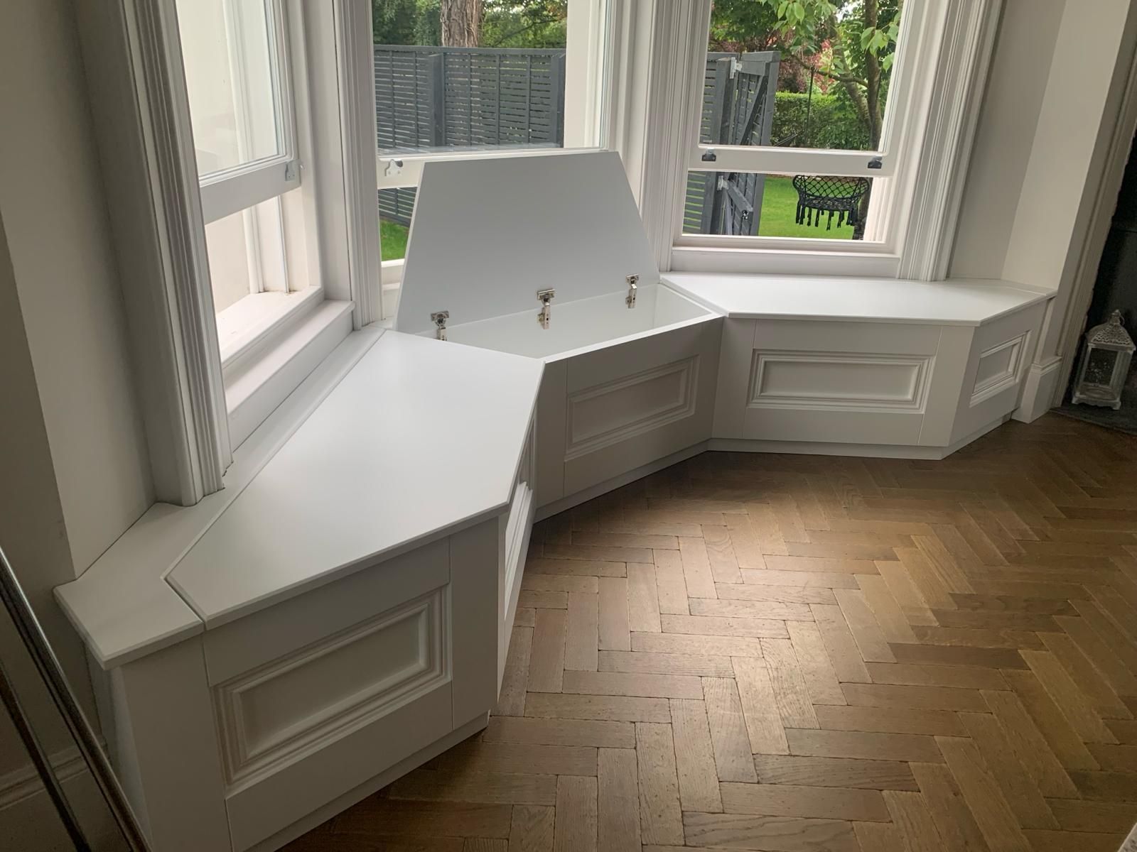 there is a window seat with a storage box underneath it .