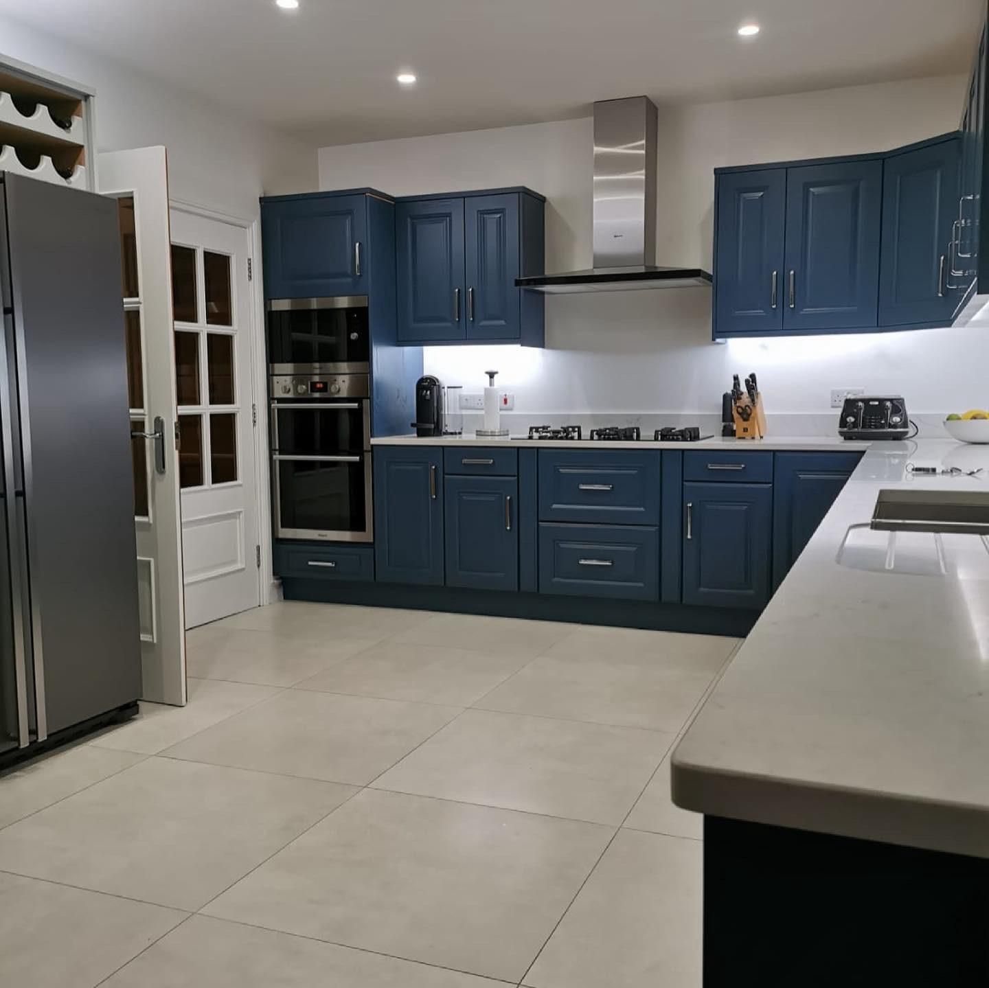 a kitchen with blue cabinets and a stainless steel refrigerator