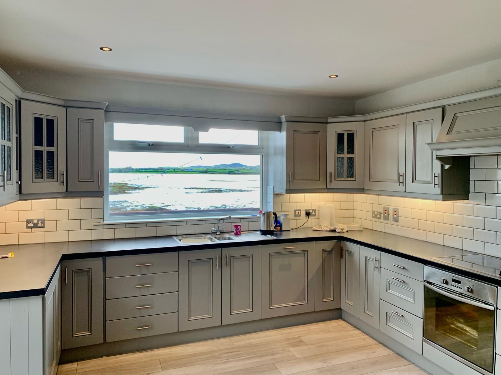 a kitchen with gray cabinets and a window overlooking a body of water