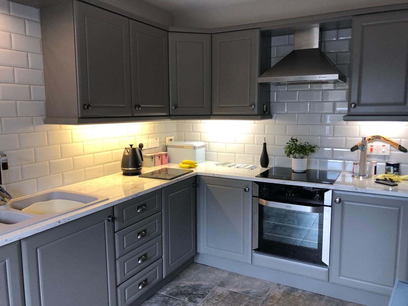 a kitchen with gray cabinets , a stove , a sink , and a hood .