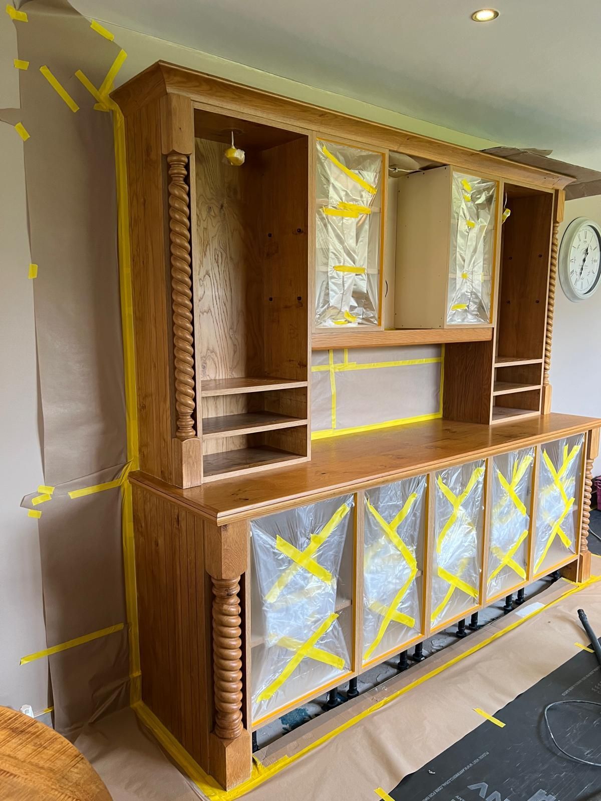 A large wooden cabinet is being painted in a living room.