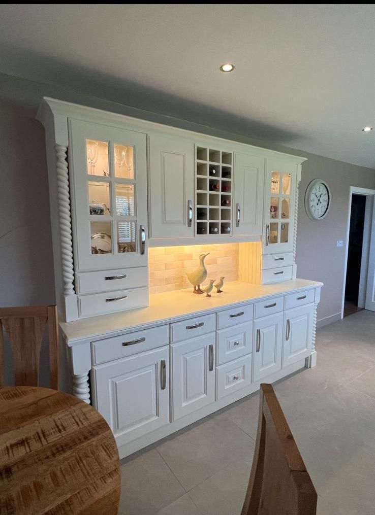 A kitchen with white cabinets , drawers , and a wine rack.