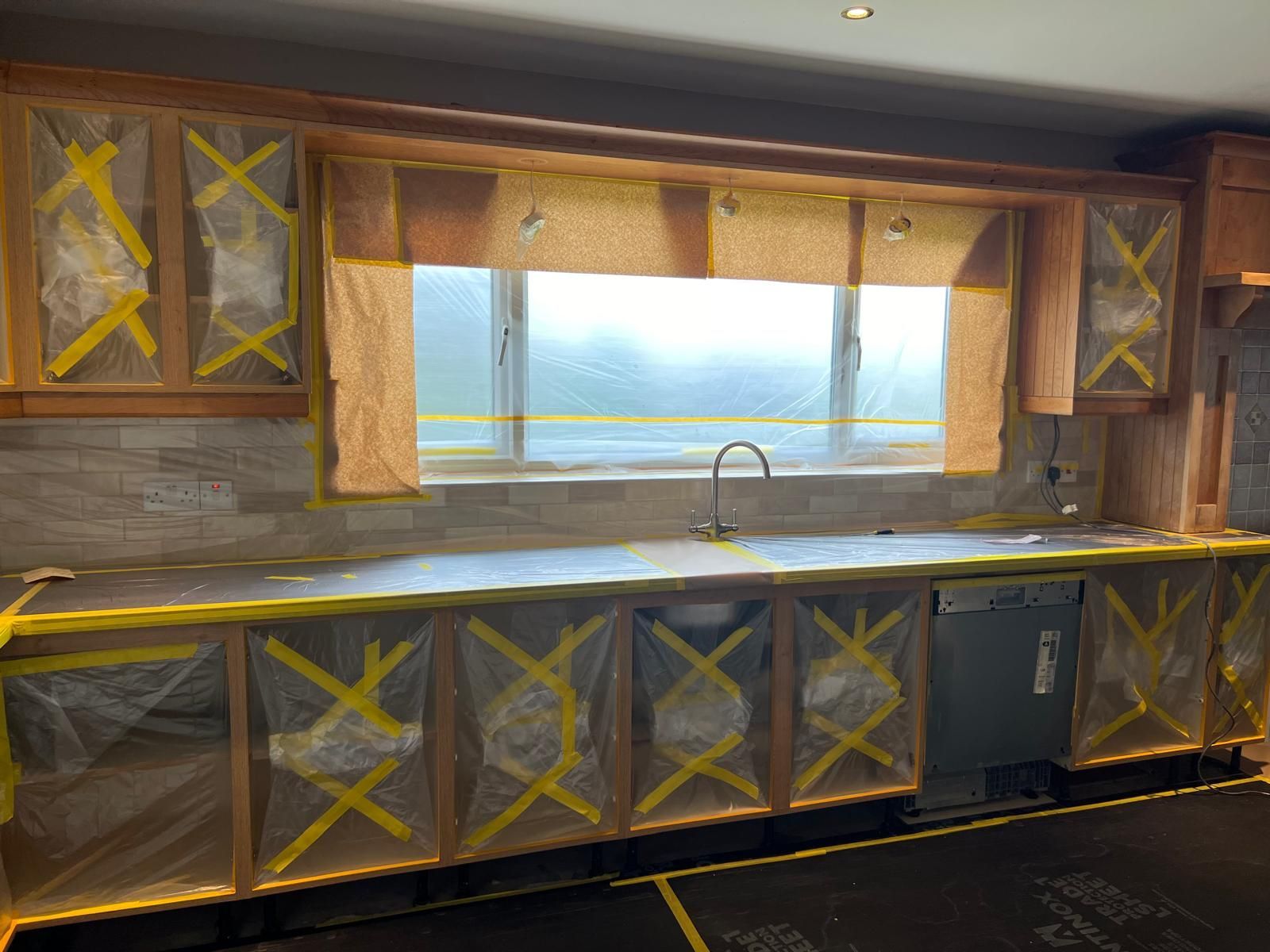 A kitchen with a sink and cabinets covered in yellow tape.
