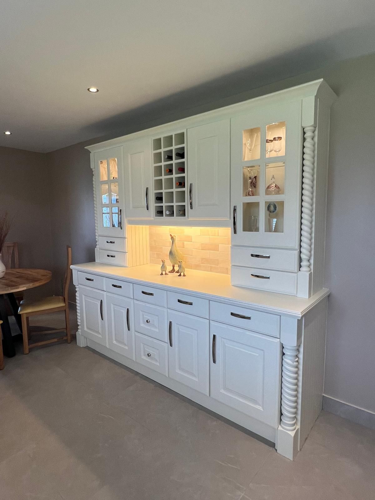A kitchen with white cabinets and a wine rack.