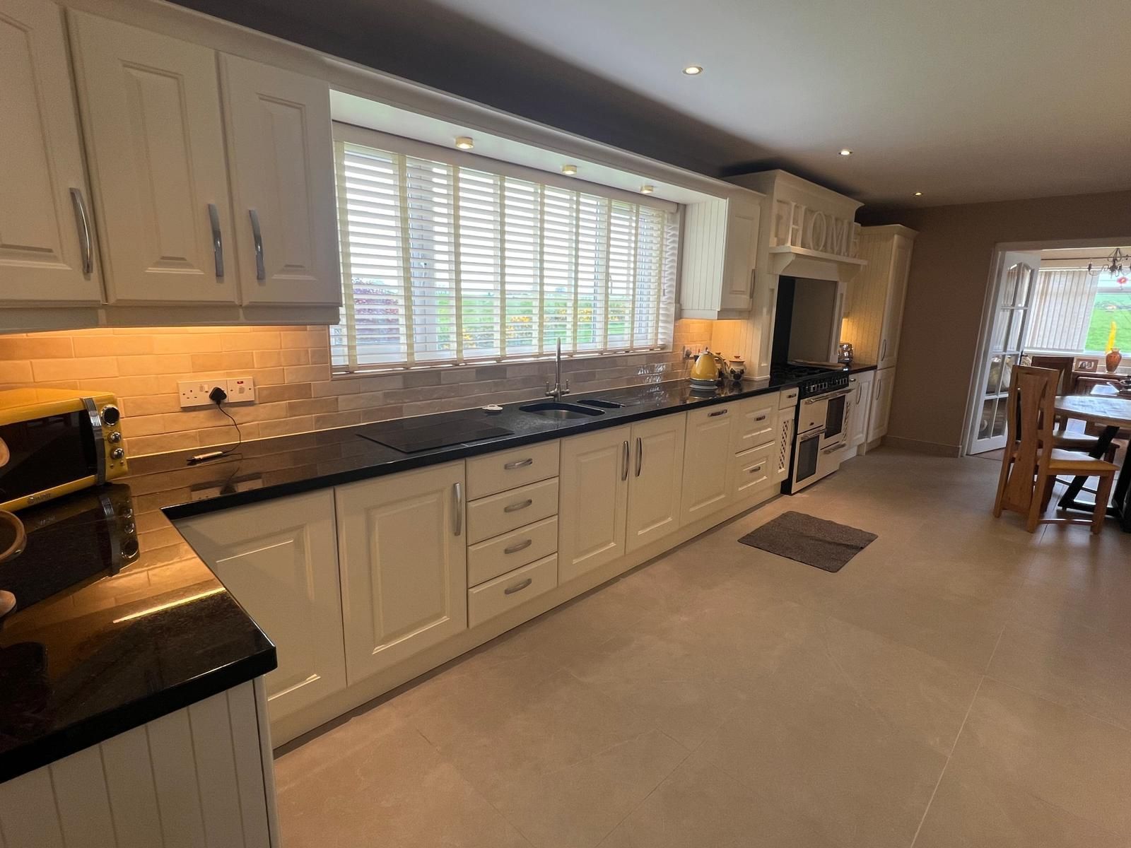 A kitchen with white cabinets and black counter tops in a house.