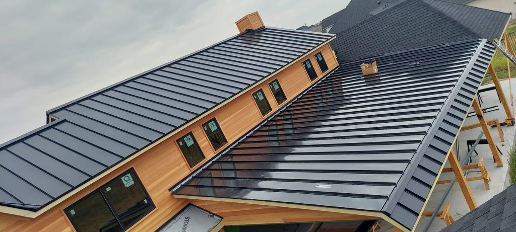 Aerial view of a modern building with a dark gray metal roof and orange-brown walls under cloudy skies