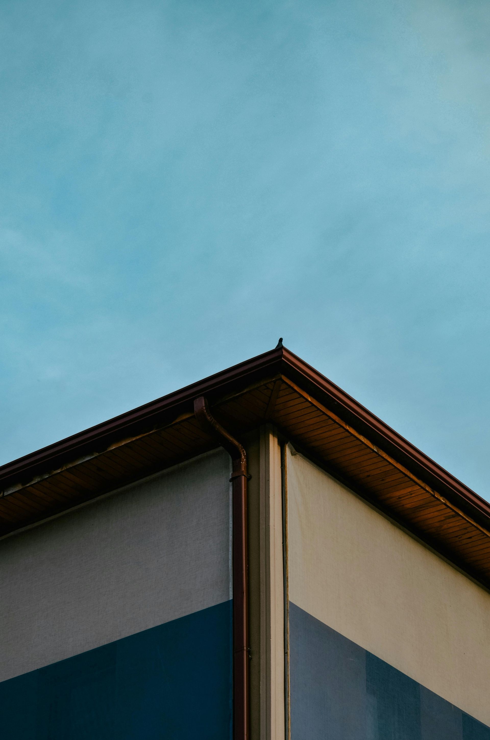 Corner of a building with a teal and white facade against a blue sky