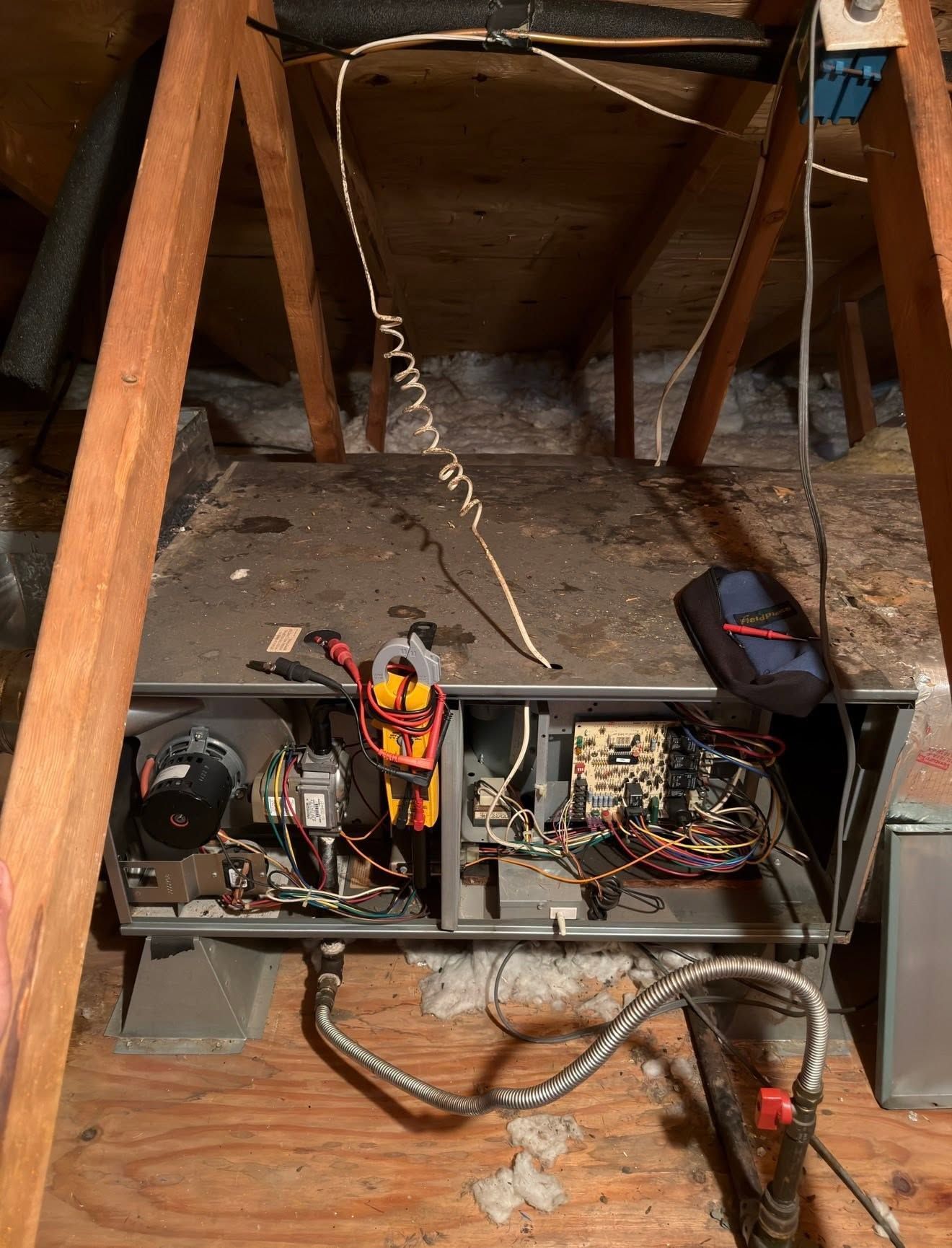 Outdoor HVAC service scene with a gray condenser unit, gauges, and tools on the ground