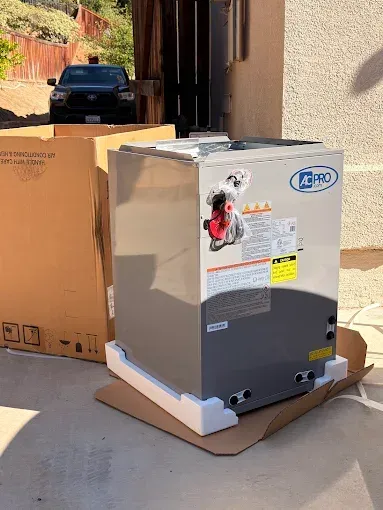 New white appliance on cardboard in driveway, with shipping labels and boxes nearby