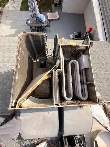 Open rooftop utility box with pipes, hoses, and wiring in a narrow outdoor courtyard.