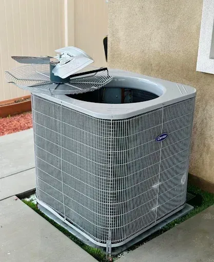 Outdoor air conditioner unit with its top cover removed, showing damaged fan blades.