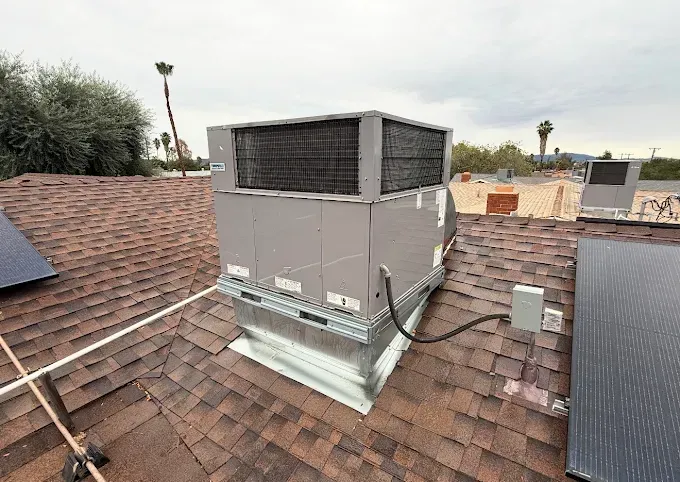 Rooftop HVAC unit on a shingled roof with nearby vents and overcast sky