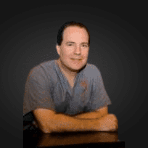 A smiling doctor in a lab coat with a stethoscope around his neck.