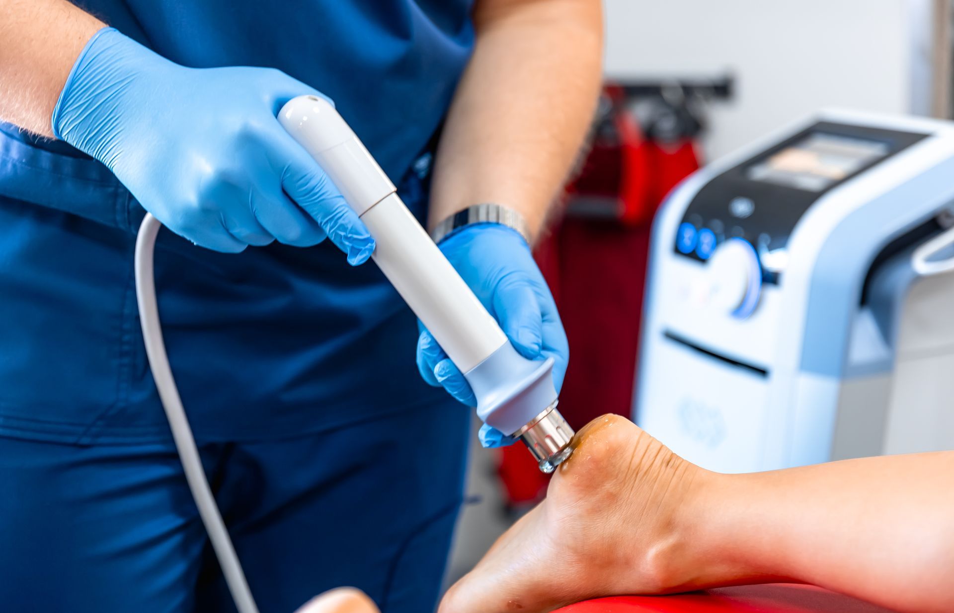Doctor using a medical device on a patient's foot. Blue gloves, equipment, setting.