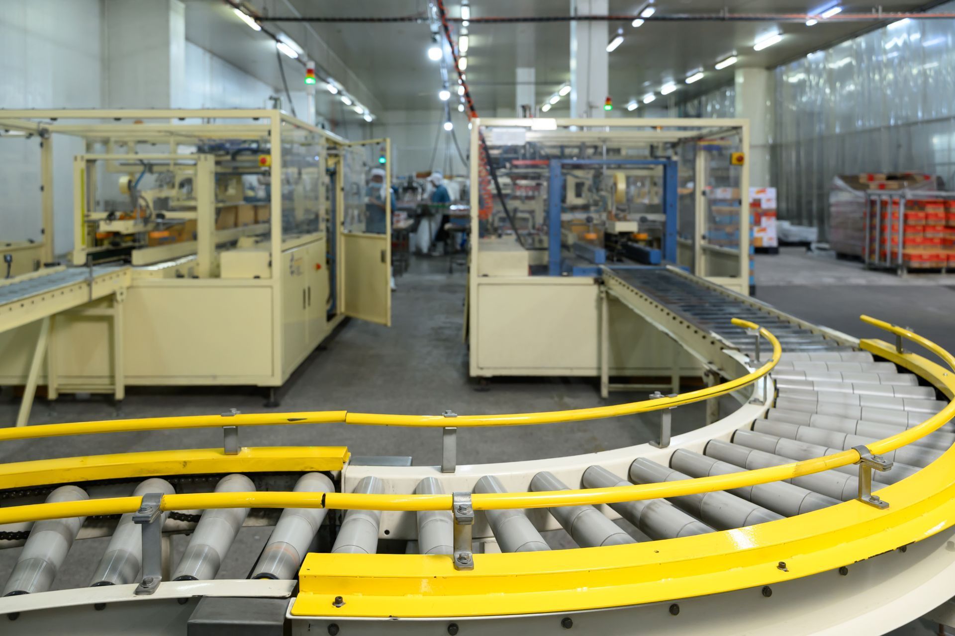 Industrial conveyor line with yellow guardrails and machinery in a factory hall