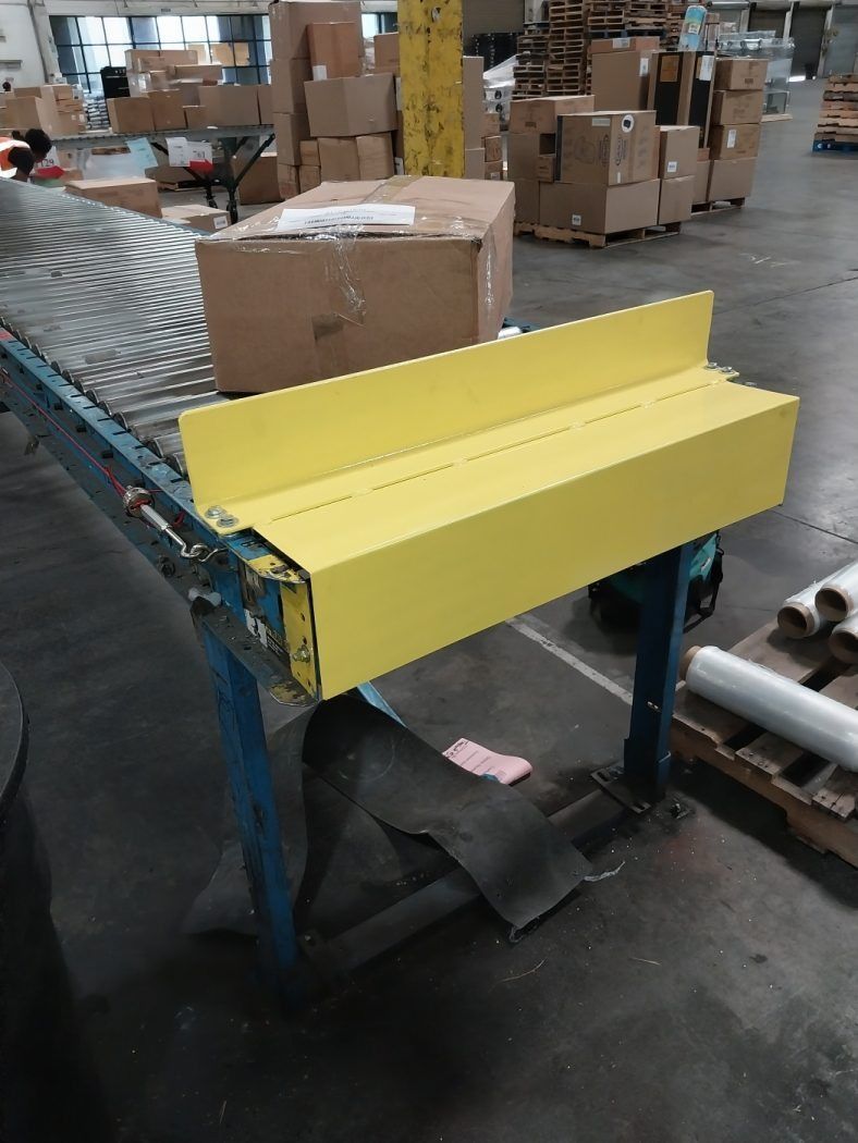 Yellow guard on warehouse conveyor with cardboard boxes in the background
