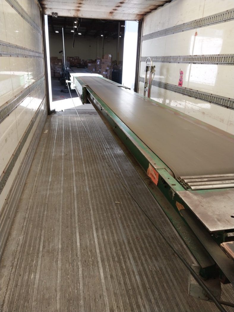 Long metal conveyor belt inside a cargo truck trailer.