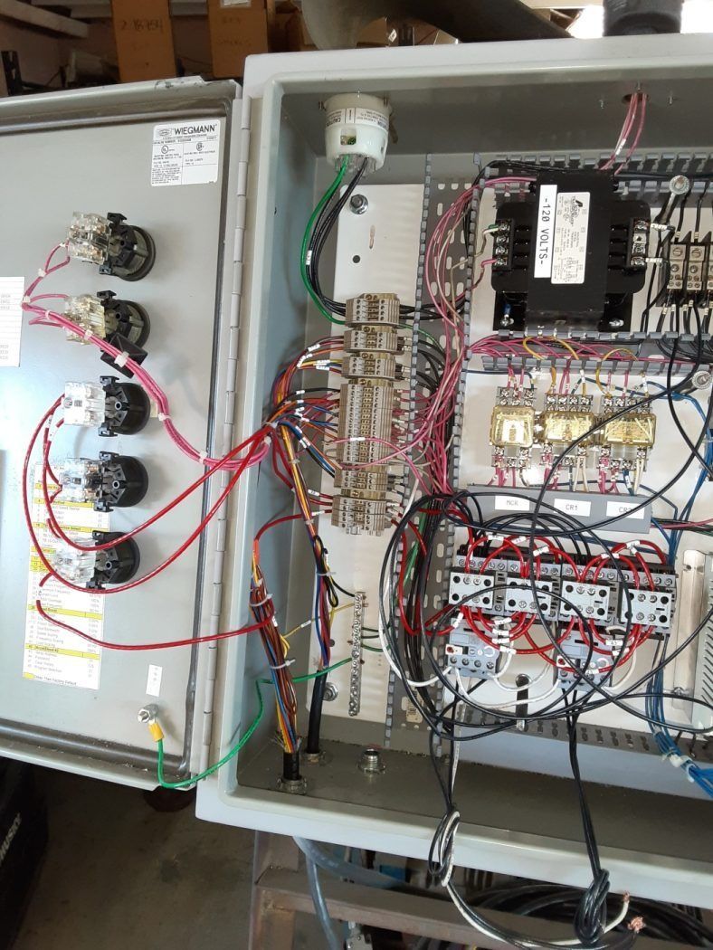 Open electrical control cabinet with wiring, relays, and terminal blocks exposed