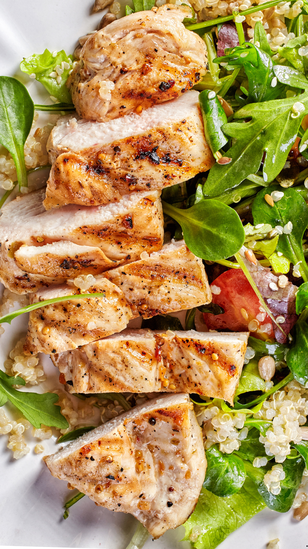 A close up of a plate of food with chicken and vegetables on a table.