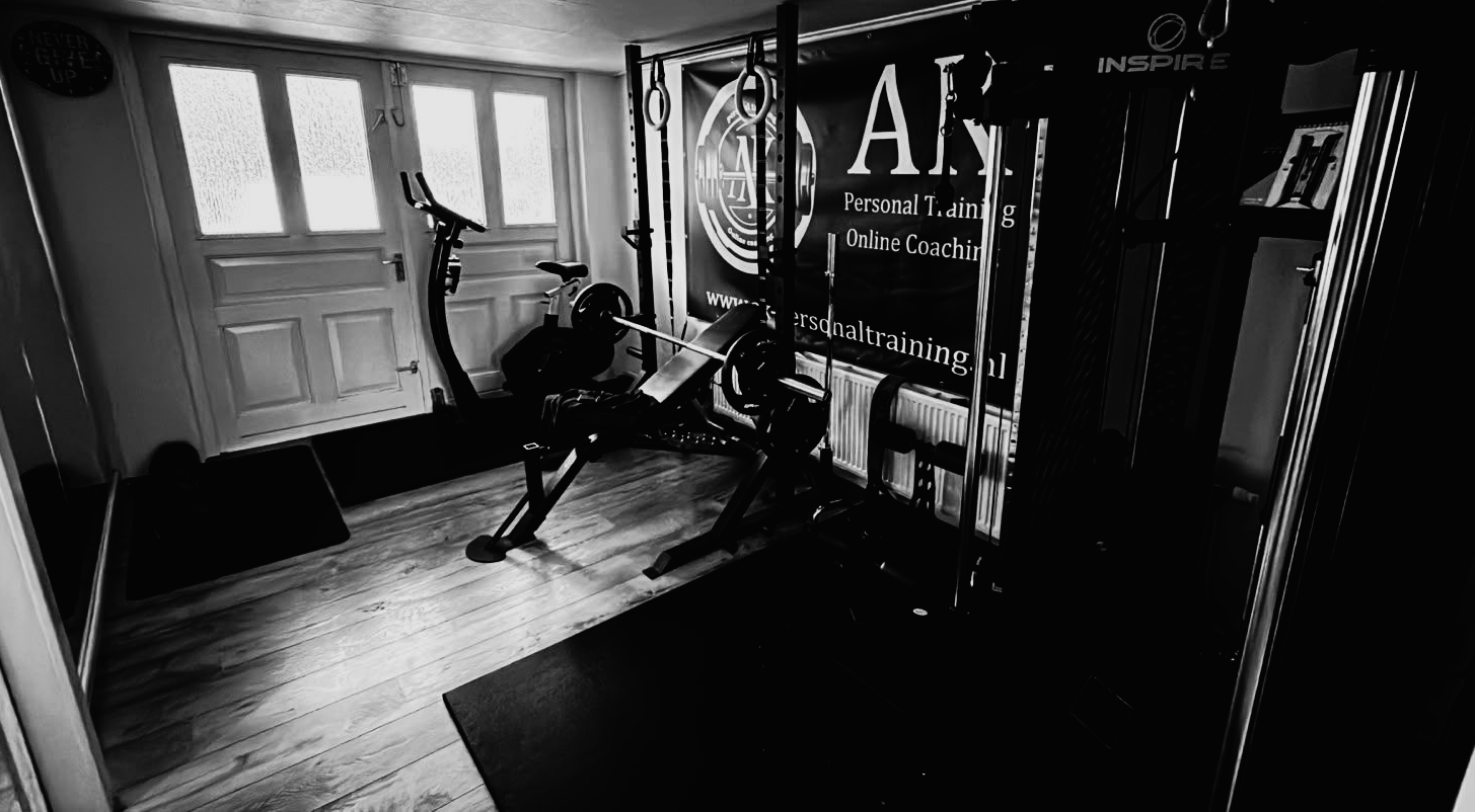 Fitnessruimte voor thuis met gewichtenrek, gewichtsapparaat, gewichten en ringen.