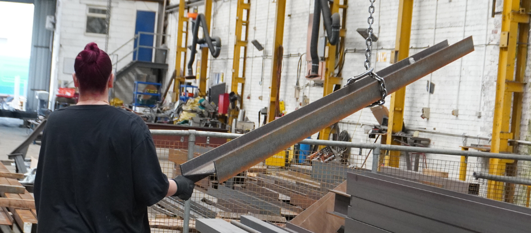 Worker moving steel in workshop