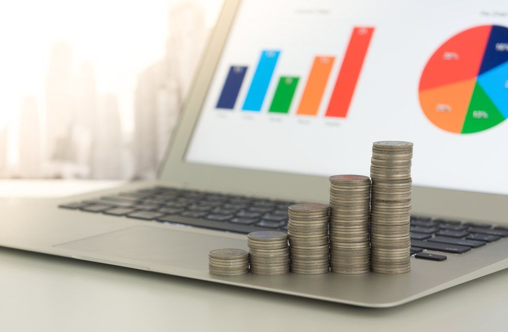 Stacks of Coins and Graph on Laptop — Accountants & Bookkeepers in Southern Highlands