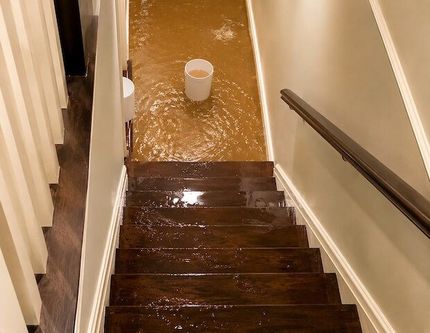 Floodwater covering a home’s lower level and wooden staircase, showing the need for emergency water damage restoration and structural drying services. Flood — Weyauwega, WI — Badgerland Restoration & Remodeling Inc.