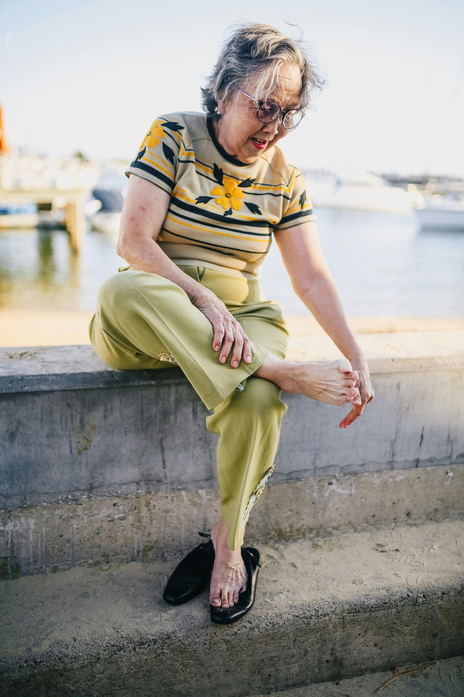 Woman sitting, touching foot, near water