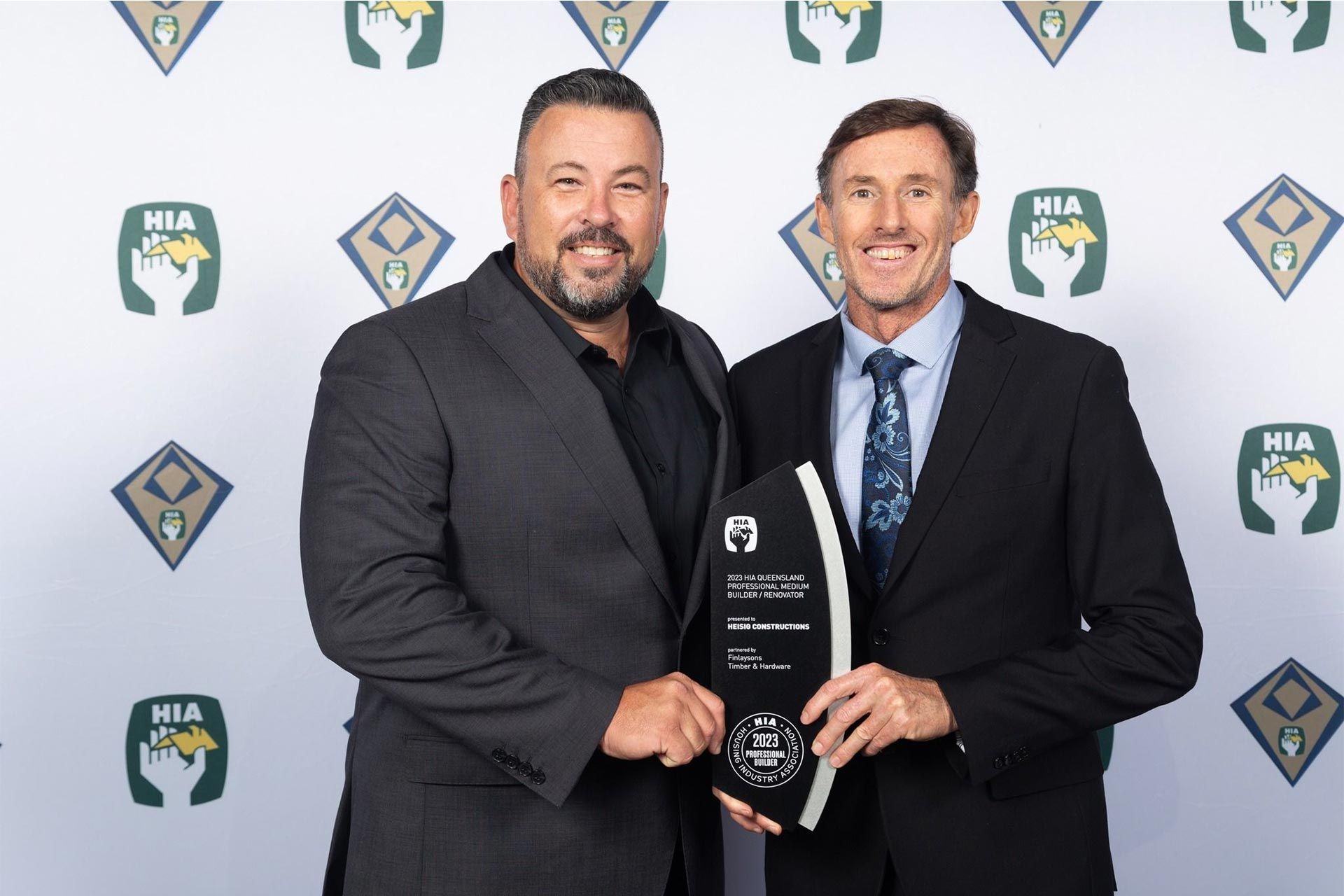 two men are standing next to each other holding a trophy .