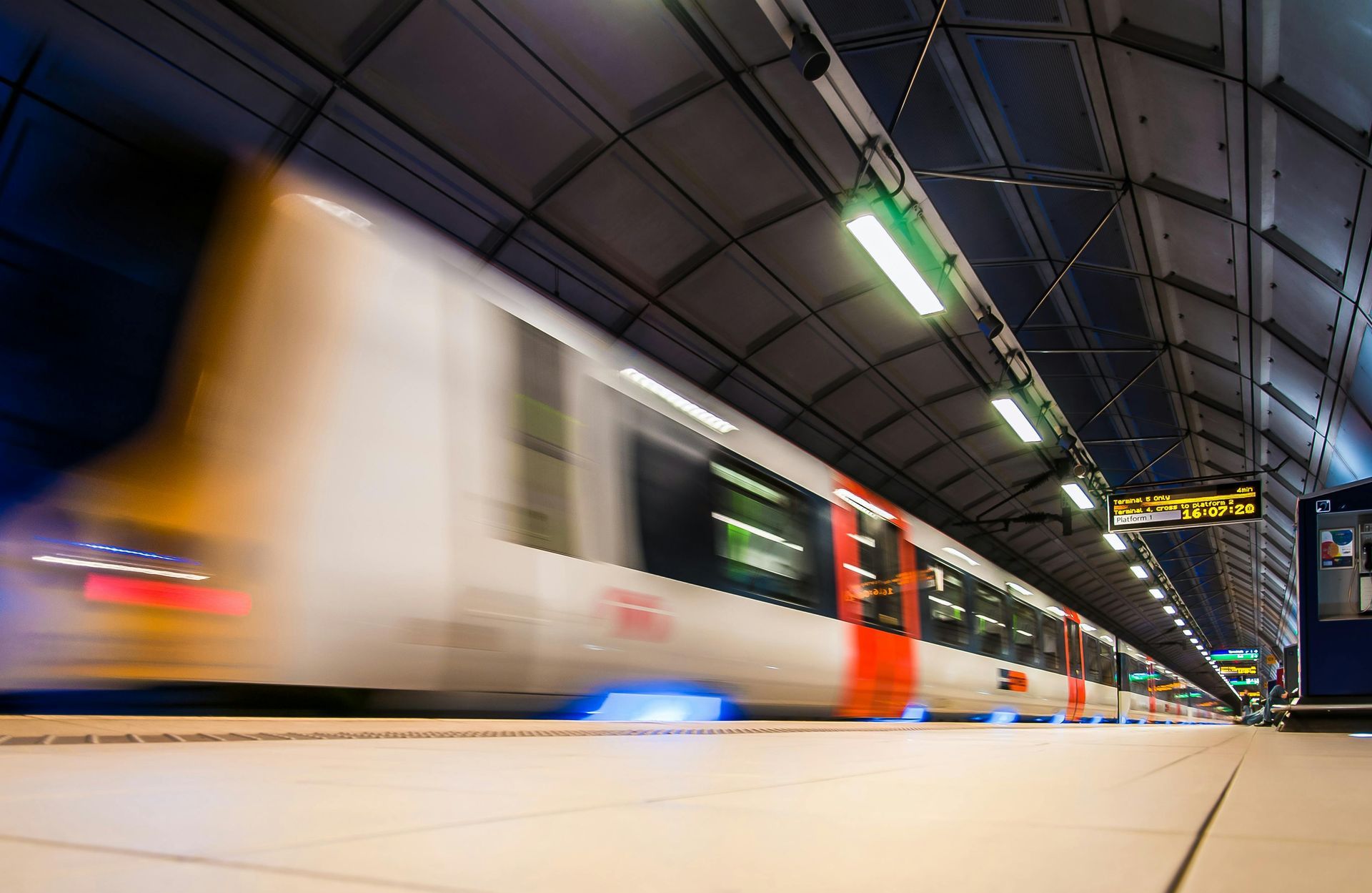 Blurred view of a speeding train in a subway station with bright lights.