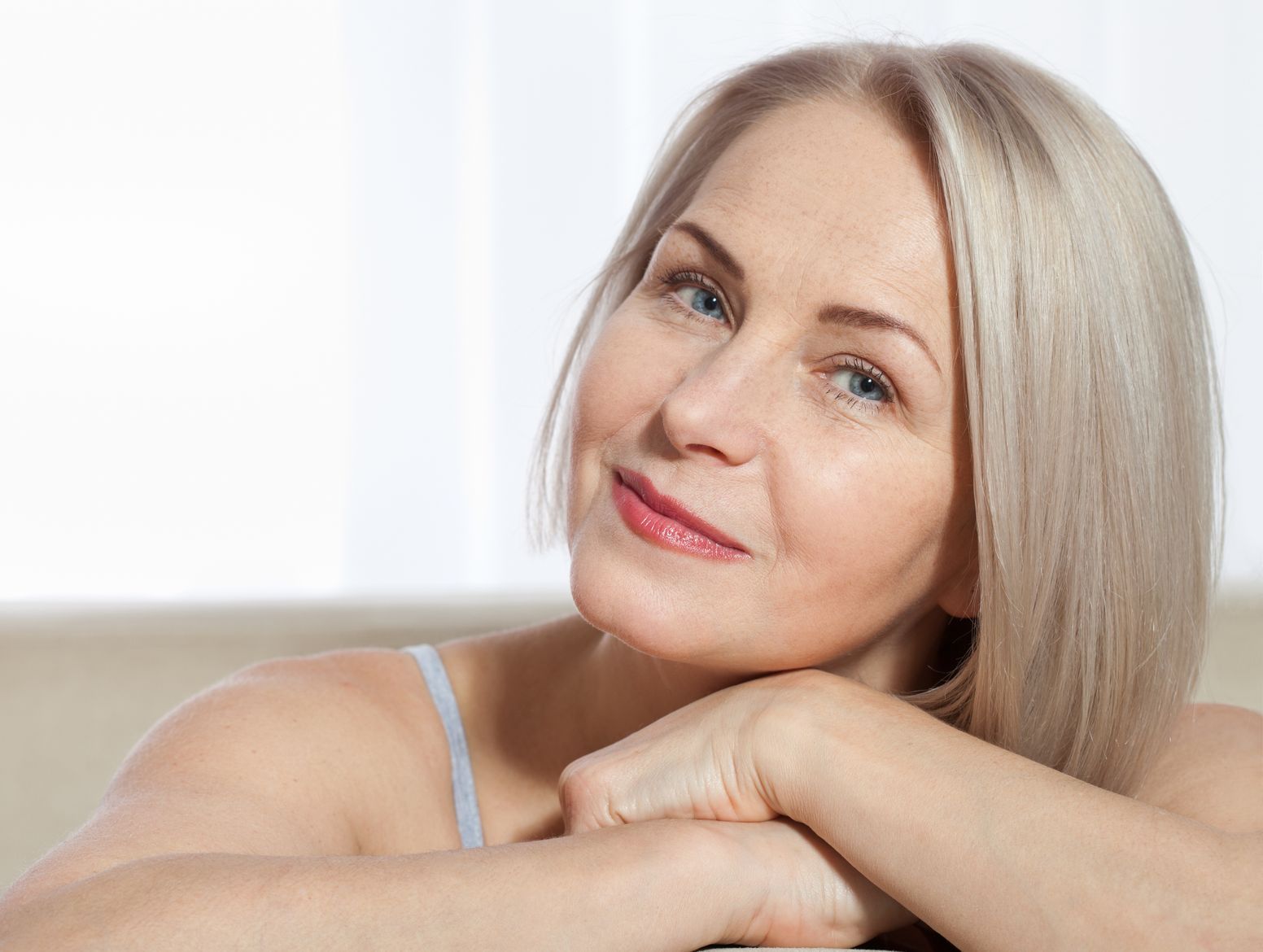 A woman is sitting on a couch with her hands on her face.