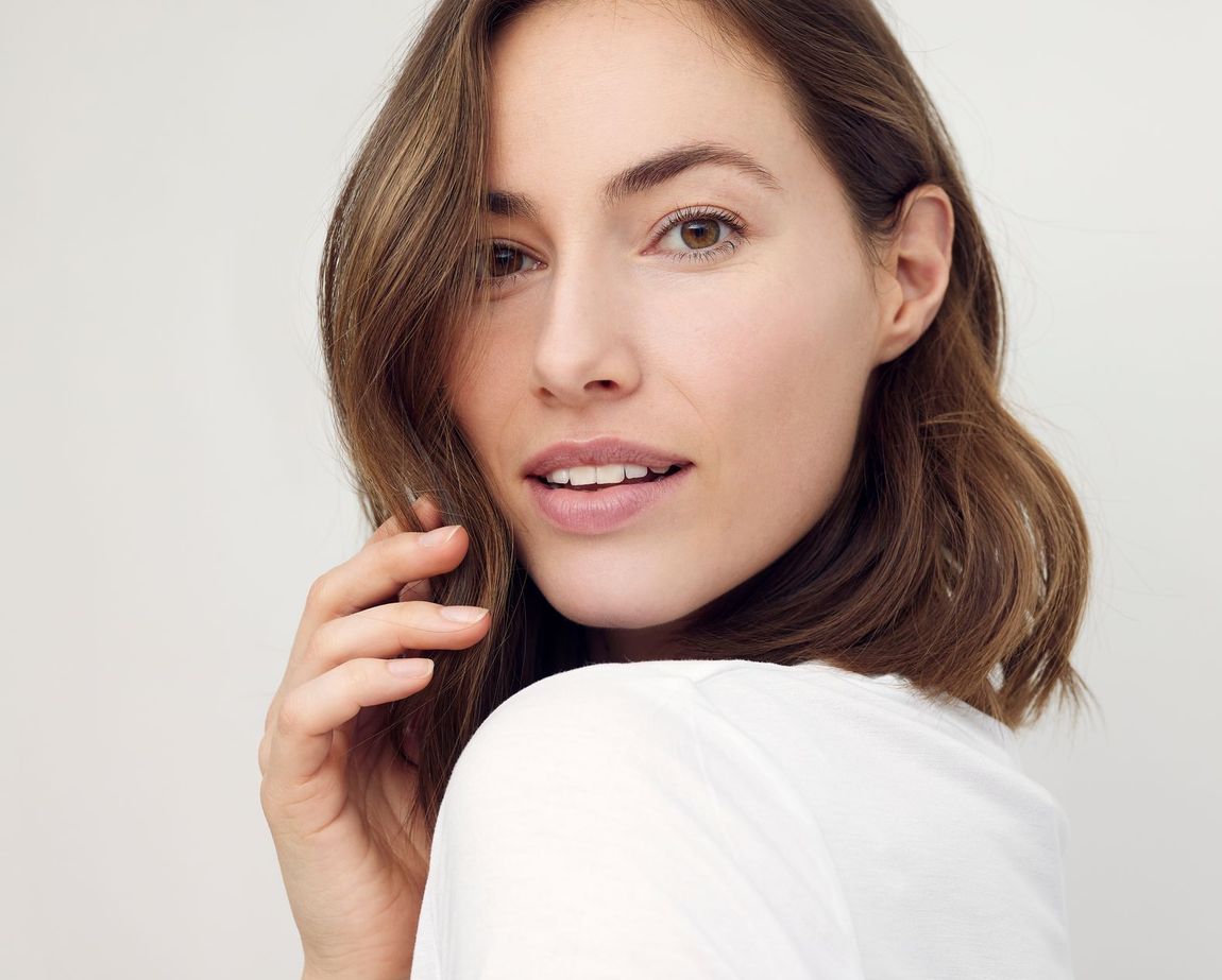 A close up of a woman 's face with her hand on her hair.