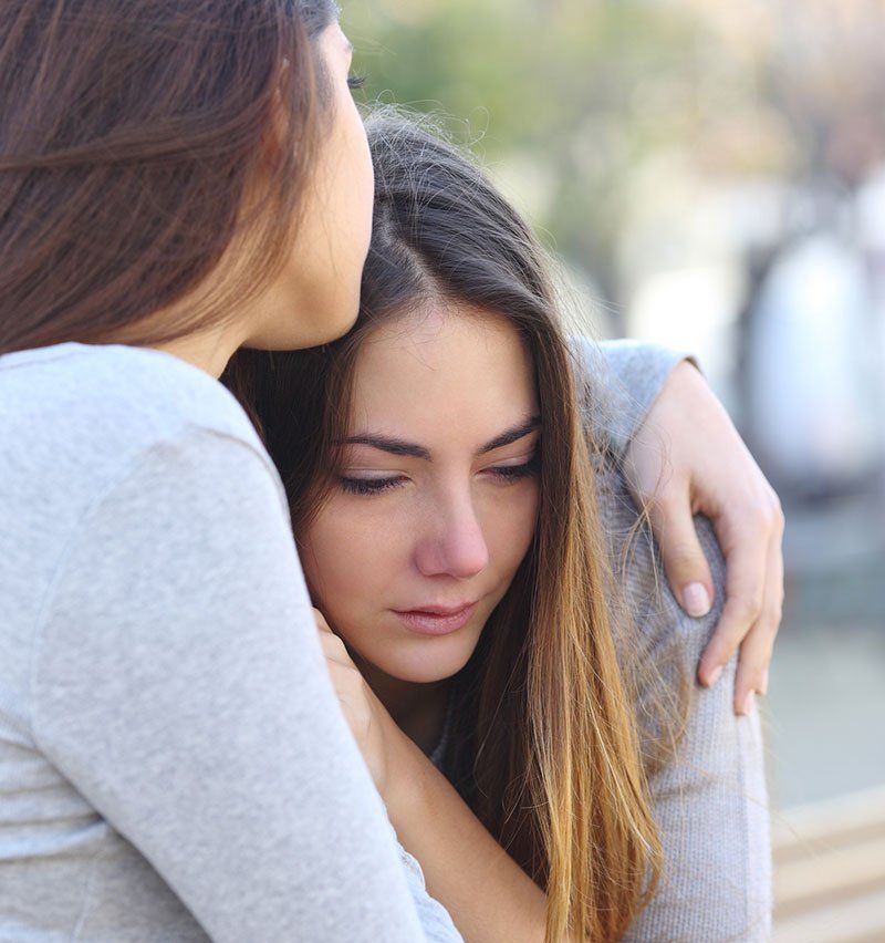 Woman hugging woman in grey shirt