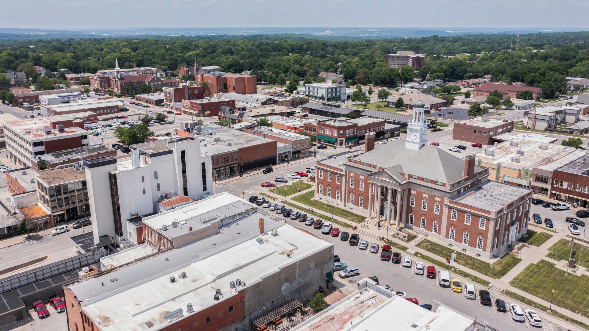 Aerial view of a downtown with brick buildings, streets, and parked cars on a clear day