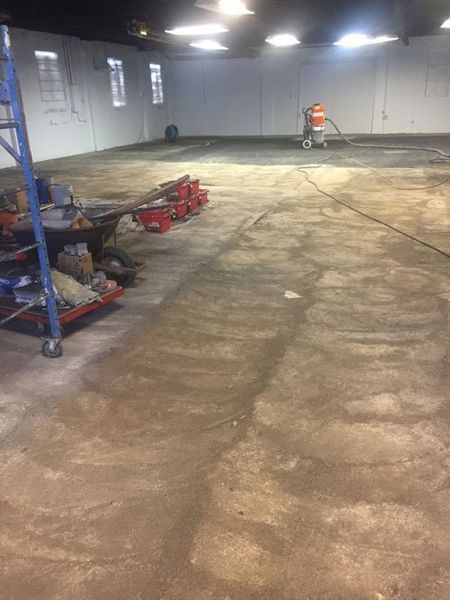 A large empty warehouse with a vacuum cleaner on the floor.