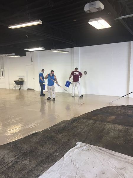 A group of men are cleaning a large empty room