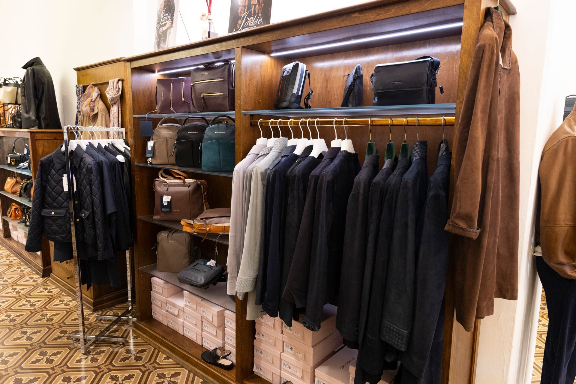 Scaffali di una boutique di abbigliamento con giacche, camicie e borse in pelle in mostra.