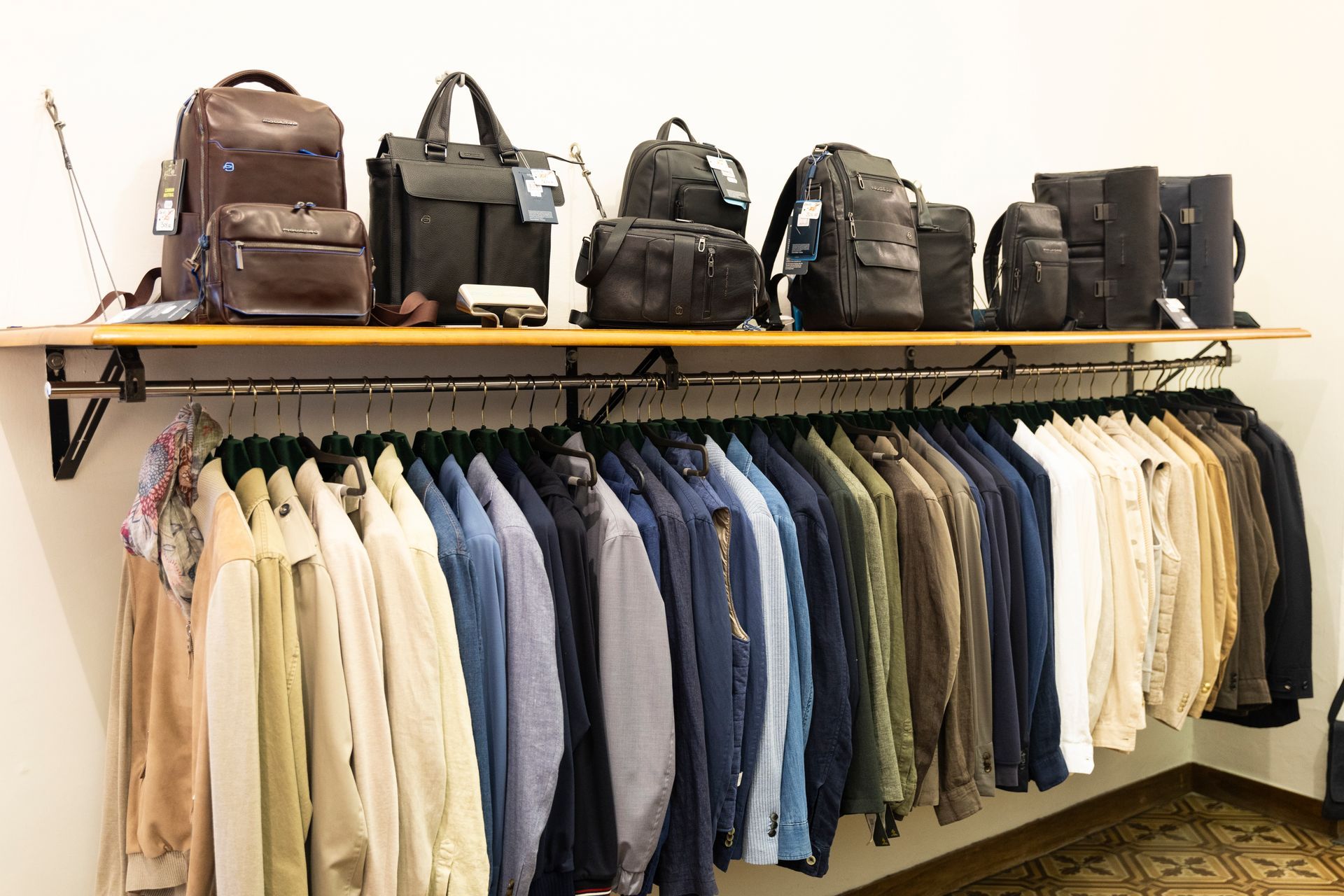 Appendiabiti con magliette e zaini assortiti esposti in un negozio o in uno showroom.
