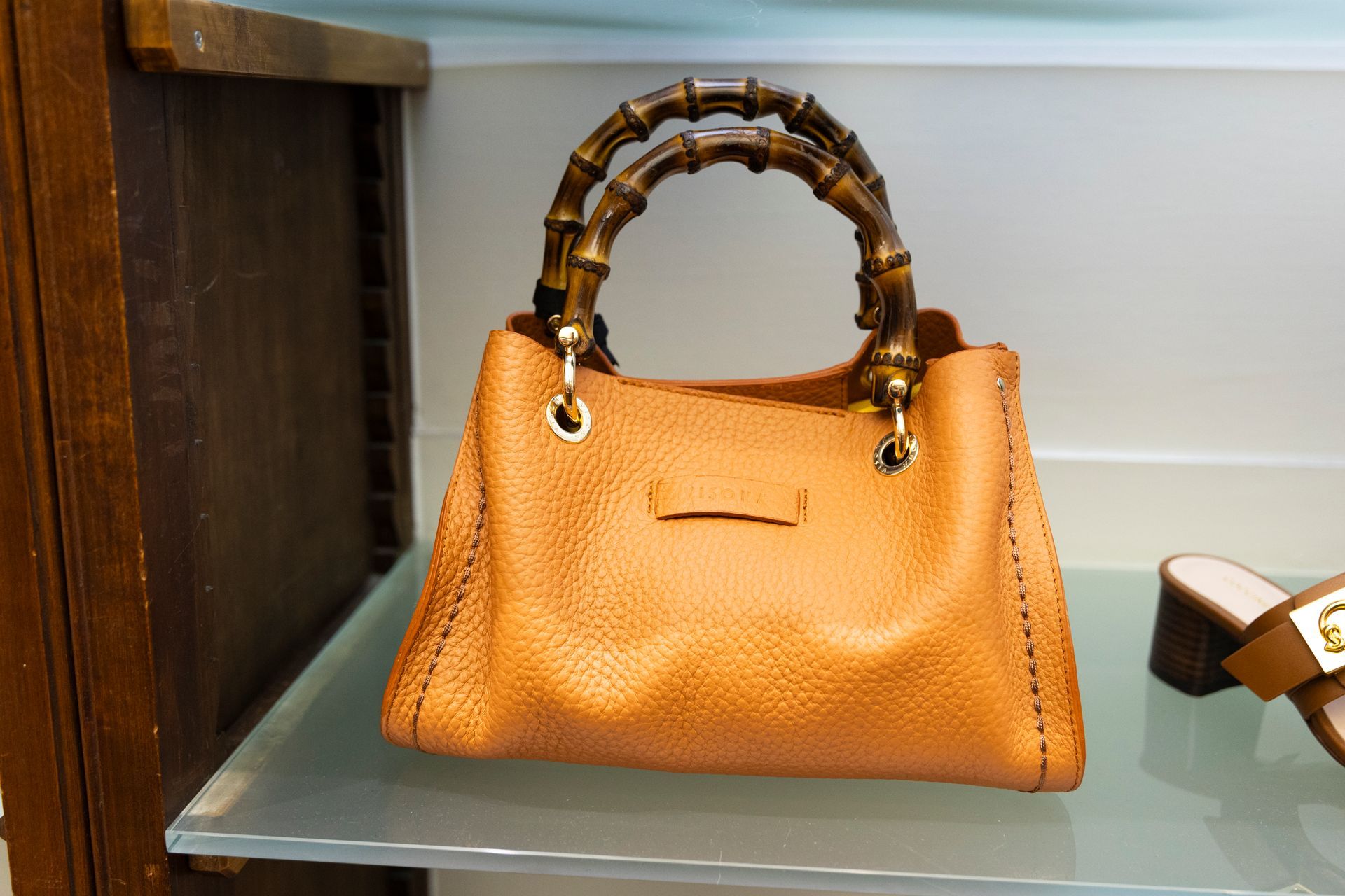 Borsa in pelle color cuoio con manici in stile bambù esposta su uno scaffale