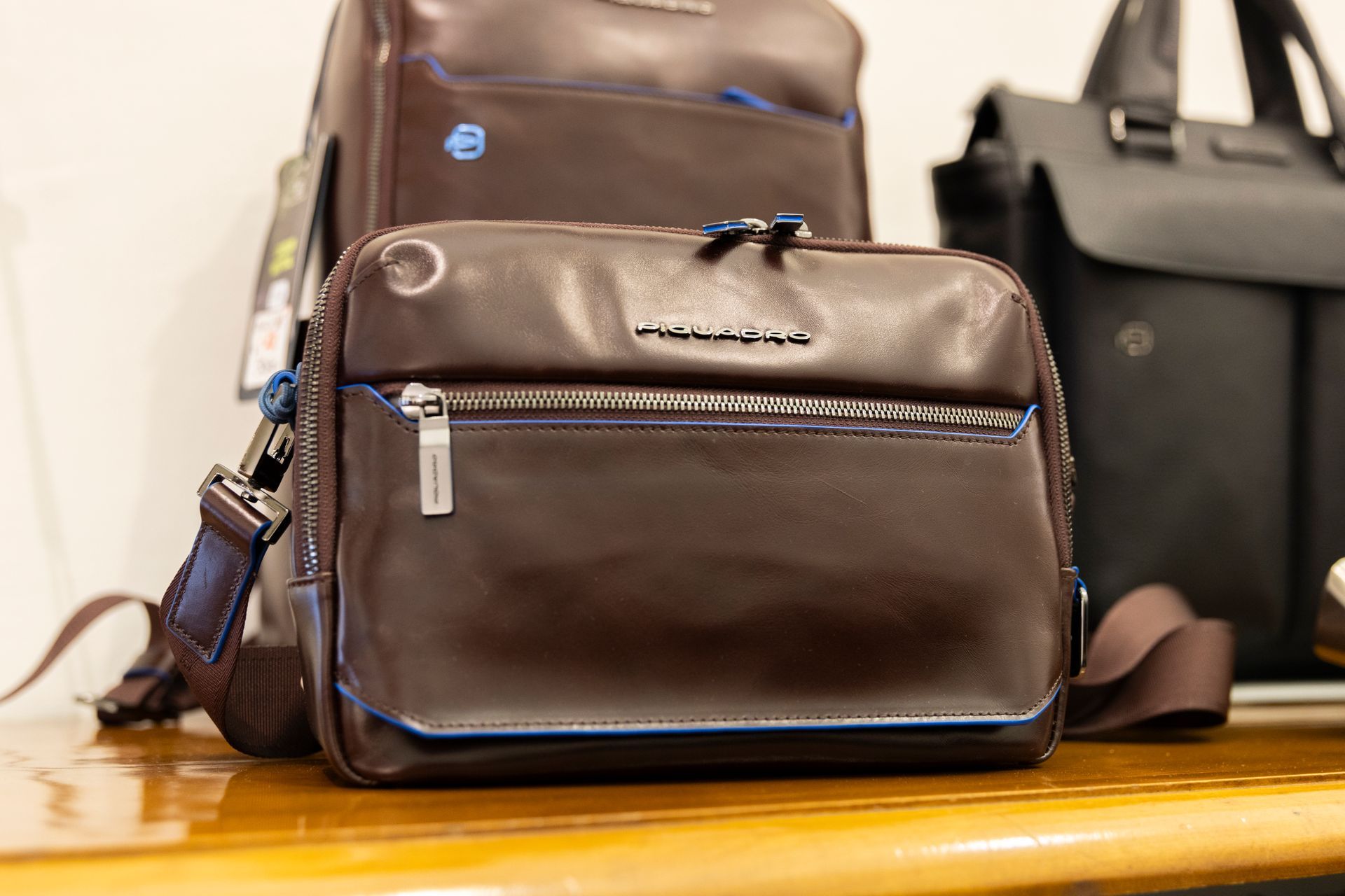 Valigetta in pelle marrone e borsa abbinata su un tavolo di legno in una vetrina di negozio.